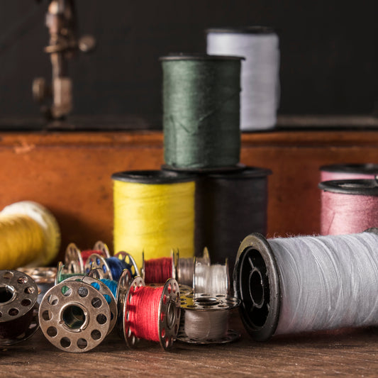 Spools of colorful thread lined up in preparation for embroidery, symbolizing creativity and craftsmanship in product creation.